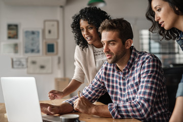 Three diverse designers using a laptop together at work