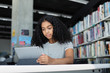 © ReeldealHD images - High school african american female student studying with digital tablet in library