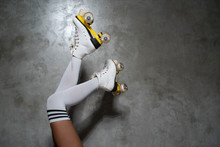 Closeup Of Female Legs In Vintage Roller Skates Isolated Over Concrete Wall Background. Space For Text