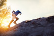 Man runs uphill on big rock at sunset
