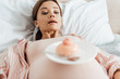 low angle view of pregnant woman lying in bed with sweet cupcake
