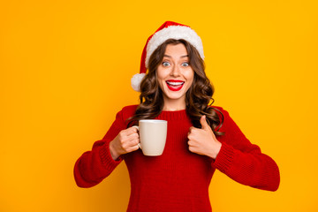 Poster - Pretty lady holding hot beverage in hands advising cool drink wear knitted jumper and santa hat isolated yellow background