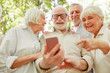 © Yakobchuk Olena - Cheerful elderly people using modern cellphone outdoors