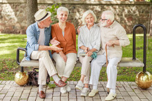 Cheerful Old People Sitting On Bench And Talking