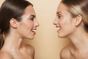 Poster - Optimistic beautiful blonde and brunette women talking with each other laughing.