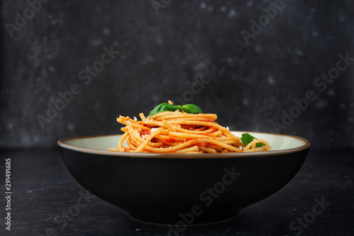 Fotomural A plate with pasta in tomato sauce on black background