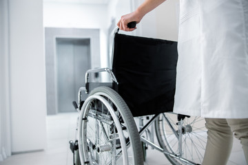 Wall Mural - Female doctor with empty wheelchair in lobby