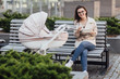© Тарас Нагирняк - Gorgeous, smilling mother holding plastic lunch box while sitting on bench with stroller and newborn baby. Feeding time.