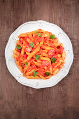 Wall Mural - Penne pasta with tomato sauce and parsley, shot from above on a dark rustic wooden background with a place for text