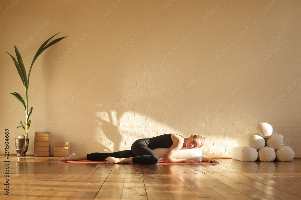 Woman practiving restorative yoga in a beautiful studio - obrazy, fototapety, plakaty 
