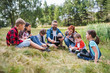 © Halfpoint - Group of school children with teacher and windmill model on field trip in nature.