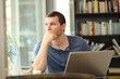 © Antonioguillem - Pensive man using laptop looks through a window in a bar