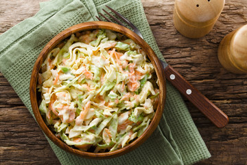 Wall Mural - Coleslaw made of freshly shredded white cabbage and grated carrot with homemade mayonnaise-based salad dressing in wooden bowl, photographed overhead (Selective Focus, Focus on the salad)