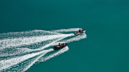 Wall Mural - Aerial drone top down photo of 2 men operating jet ski watercraft cruising in high speed in tropical exotic lake