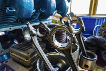 The connecting rod, piston and cylinder block in a disassembled condition in a car workshop.