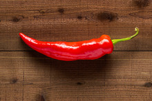 One Red Banana Pepper On A Textured Dark Wood Planks Background