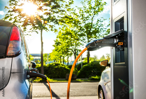 Fotografía Elektroautos an Ladestation auf Firmengelände im Gegenlicht – Electric Car at Ch