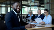 © motortion - Happy afro-american businessman smiling camera sitting office table, career