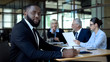 © motortion - African office worker looking camera, business partners talking on background