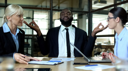 Wall Mural - Businessman meditating in office, tired of female colleagues conflict at work