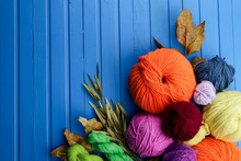Composition With Yarn Balls And Autumn Leaves On Color Wooden Background