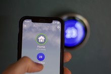 Cell Phone Changes Temperature Of Smart Home Thermostat. Temperature Is Visible In Celsius On Phone Screen And Nest.