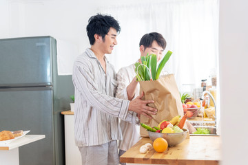 Asian gay couple homosexual cooking together in the kitchen prepare fresh vegetable make organic salad healthy food. Asian people happy time smile, laugh in kitchen. LGBTQ relation lifestyle concept