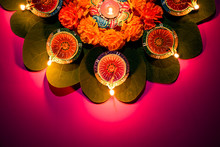 Happy Dussehra. Clay Diya Lamps Lit During Dussehra With Yellow Flowers, Green Leaf And Rice On Pink Pastel Background. Dussehra Indian Festival Concept.