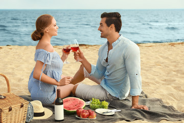 Poster - Beautiful young couple having picnic at sea beach