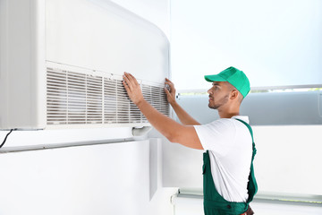 Wall Mural - Professional technician maintaining modern air conditioner indoors