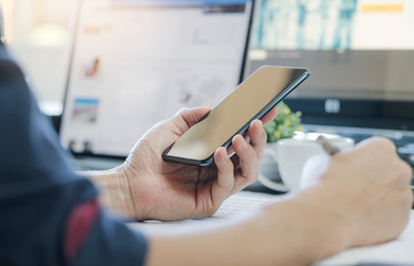 Wall Mural - man using smartphone while working at modern office, blank screen for graphics display.