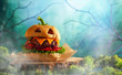 Halloween party burger in shape of scary pumpkin  on  wooden board. Halloween food concept.