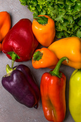 Wall Mural - Bell Peppers, sprig green lettuce on grey background