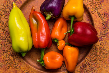 Wall Mural - Red, green, purple, orange, yellow sweet bell peppers on golden plate