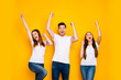 Portrait of three nice attractive lovely cheerful cheery person celebrating cool attainment having fun rising hands up isolated over bright vivid shine yellow background