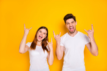 Poster - Portrait of cool two people with long haircut making horns screaming wearing white t-shirt isolated over yellow background