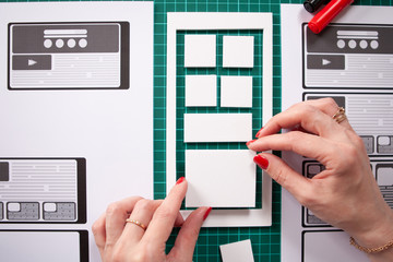 Girl creates a prototype application. UX mobile app design. The process of creating an application. Visualization for phone applications. She thinks the structure of the application designer.