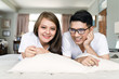 © amornchaijj - Asian young couples wearing white T-shirts are relaxing and smiling in bed.