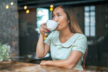 A woman sitting and drinking coffee in a coffee shop