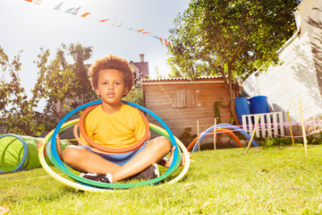 Wall Mural - Happy black boy sit with hula rings on grass