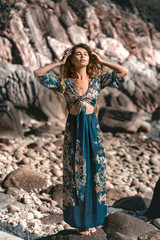 Wall Mural - beautiful young woman in stylish boho dress posing outdoors at sunset