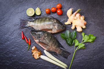 Wall Mural - Tilapia fish freshwater and lime herb vegetable for cooking food in the asian restaurant - Fresh raw tilapia on wooden background