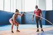 © Alessandro Biascioli - Fit woman training with battle rope inside gym - Personal trainer motivating a female athlete doing workout session exercises - Wellness, sport lifestyle concept
