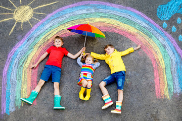 three little children, two school kids boys and toddler girl having fun with with rainbow picture dr