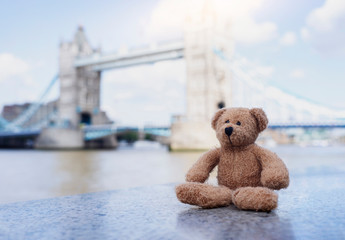 Wall Mural - Teddy bear sitting alone with blurry london tower bridge background, The forgotten bear sitting by the river, lost property, Lonely concept, Lost child, International missing child