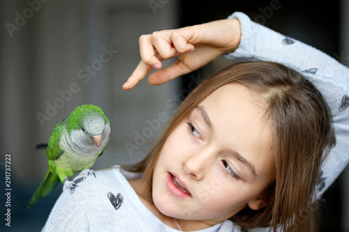 Fotomural Cute tween girl playing with her pet green Monk Parakeet parrot