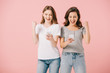 © LIGHTFIELD STUDIOS - attractive and smiling women in t-shirts holding smartphones and showing yes gesture isolated on pink