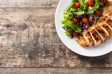 Poster - Grilled chicken breast with vegetables on a plate on wooden table. Top view. Copy space