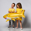 © FAB.1 - little girl in a yellow dress wants to pick up a shark balloon from her friend or brother