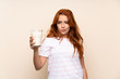 © luismolinero - Teenager redhead girl holding a glass of milk over isolated background with sad expression